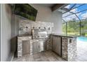 Outdoor kitchen featuring stone countertops, a stainless steel grill, and a mini-fridge at 12539 Wetmore Ct, Odessa, FL 33556