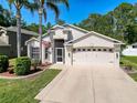 Well-maintained two-story home with a manicured lawn, mature trees, and a spacious driveway at 13850 Royston Bnd, Hudson, FL 34669