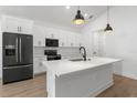 Modern kitchen features white cabinets, stainless steel appliances, a large island, and sleek black accents at 14042 Amero Ln, Spring Hill, FL 34609
