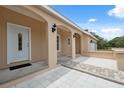 Inviting front porch with white columns, neutral stucco and tiled entry leading to the front door at 14740 Loma Ave, Spring Hill, FL 34610