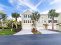 Three-story townhome featuring a two car garage, palm trees, and manicured landscaping at 3119 Oyster Bayou Way, Clearwater, FL 33759