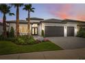 Stunning home at twilight boasting mature palms, landscape lighting and spacious paver driveway and 2-car garage at 3915 Corsica Pl, Wesley Chapel, FL 33543