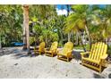Private beach area with comfortable yellow Adirondack chairs under the shade of palm trees at 4541 School Rd, Land O Lakes, FL 34638