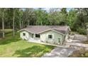 Charming single story home with a light green exterior and spacious front yard surrounded by mature trees at 5113 Cedar Ln, Brooksville, FL 34601