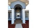 Inviting front entryway with white columns and an arch that frames the decorative glass front door at 5294 Elkin Ave, Spring Hill, FL 34606