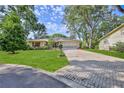Beautiful single-story home with manicured lawn, brick driveway, and mature trees, showcasing its curb appeal at 6172 Prestwick Ct, Spring Hill, FL 34606