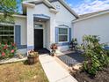 Inviting front porch with a walkway, black door, and colorful landscaping at 6273 Pinehurst Dr, Spring Hill, FL 34606
