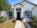 Inviting front porch with a walkway, black door, and colorful landscaping at 6273 Pinehurst Dr, Spring Hill, FL 34606
