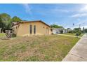 A cozy yellow home featuring a well-maintained lawn and a sunny sky backdrop at 7035 Cutty Sark Dr, Port Richey, FL 34668