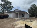 A charming single-story home featuring a gray exterior, a two-car garage, and covered front porch, surrounded by natural landscaping at 7583 St Andrews Blvd, Weeki Wachee, FL 34613