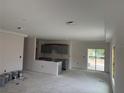 Spacious, unfinished living room area with gray kitchen cabinets and sliding doors, showing the open concept design at 7583 St Andrews Blvd, Weeki Wachee, FL 34613
