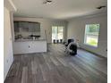 Spacious living room featuring gray vinyl plank flooring, abundant natural light, and an open concept layout at 7583 St Andrews Blvd, Weeki Wachee, FL 34613