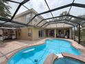 Screened-in pool with a spa and an outdoor kitchen, surrounded by a brick patio at 9124 Topneck St, New Port Richey, FL 34654