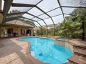 Relaxing backyard with a large screened-in pool, spa, and a brick patio at 9124 Topneck St, New Port Richey, FL 34654