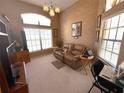 Bright living room with large windows, neutral carpet, tan leather sofa and arched window at 9311 Haas Dr, Hudson, FL 34669