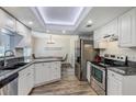 Bright kitchen featuring white cabinetry, granite countertops, stainless steel appliances, and wood-look flooring at 10910 Winter Oak Pl, Tampa, FL 33618
