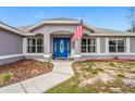 Inviting home entrance featuring a bright blue front door with decorative glass, flanked by white trimmed windows at 1219 Aladdin Rd, Spring Hill, FL 34609