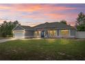 Charming single-story home with an attached garage, manicured lawn, and a welcoming blue front door during sunset at 1219 Aladdin Rd, Spring Hill, FL 34609