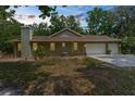 Rear exterior of the home featuring a two-car garage and serene backyard at 14145 Citrus Way, Brooksville, FL 34601