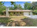 Rear exterior of the home featuring a two-car garage and serene backyard at 14145 Citrus Way, Brooksville, FL 34601