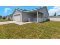 Charming single-story home featuring a two-car garage and covered front porch with white railing at 5214 Idlewild St, New Port Richey, FL 34653