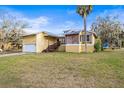 Inviting exterior of a yellow two-story home with a metal roof, attached garage, and a well-maintained front yard at 5422 Foley Sq, New Port Richey, FL 34652