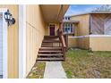 Welcoming front porch with wooden steps leading to a red front door and a decorative window at 5422 Foley Sq, New Port Richey, FL 34652