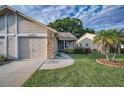 The attractive exterior features a well-kept lawn, neutral siding and a charming palm tree at 6425 Thicket Trl, New Port Richey, FL 34653