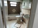 Cozy bathroom with decorative tiled walls, a tub, toilet, and pedestal sink at 7331 Sandalwood Dr, Port Richey, FL 34668