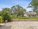 Backyard with brick patio featuring landscaped garden, lush green lawn, and shade trees in a peaceful setting at 8001 Summerbreeze Ter, Spring Hill, FL 34606