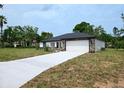 Stylish single-level home with a long driveway and attached garage, offering a contemporary design at 9482 Noddy Tern Rd, Weeki Wachee, FL 34613