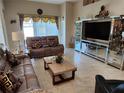 Comfortable living room featuring plush sofas, decorative curtains, and a mirrored entertainment center with a large TV at 954 Old Windsor Way, Spring Hill, FL 34609