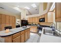Bright kitchen with an island, wood cabinets, white tile floors, and modern appliances under a skylit ceiling at 9757 Hermosillo Dr, New Port Richey, FL 34655