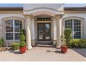 Elegant front entrance with double doors, flanked by columns and manicured greenery, creating a welcoming ambiance at 10645 Garda Dr, Trinity, FL 34655