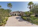 Attractive home featuring lush tropical landscaping, a spacious brick driveway, and a three-car garage in a desirable neighborhood at 10645 Garda Dr, Trinity, FL 34655