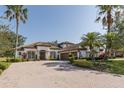 Eye-level view of a attractive home featuring lush landscaping, a spacious brick driveway, and a three-car garage at 10645 Garda Dr, Trinity, FL 34655