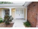 Welcoming front entrance with double doors, yellow trim and brick accents surrounded by lush landscaping at 12411 Yorktown Ln, Hudson, FL 34667
