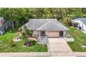 Overhead view of the single-story home with lush landscaping, mature trees, and an attached two-car garage at 13003 Sandburst Ln, Hudson, FL 34667