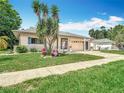 Traditional single-story home boasting a manicured lawn, colorful flowerbeds, and an attached two-car garage at 13003 Sandburst Ln, Hudson, FL 34667