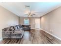 Bright living room featuring hardwood floors, a ceiling fan, and a comfy gray sectional sofa at 15846 Stable Run Dr, Spring Hill, FL 34610