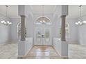 Grand foyer featuring elegant double doors, chandelier, tile flooring, and architectural columns at 18644 Autumn Lake Blvd, Hudson, FL 34667