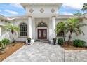 Elegant entryway featuring double doors, columns, manicured landscaping, and a patterned paver walkway at 18644 Autumn Lake Blvd, Hudson, FL 34667