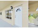 View of front entrance to unit 40 with sconce, white door and railing nearby stairs at 2402 Ecuadorian Way # 40, Clearwater, FL 33763