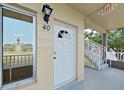 A close-up of the front entrance to unit 40, featuring a white door, sconce, and nearby stairs at 2402 Ecuadorian Way # 40, Clearwater, FL 33763