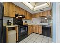 Functional kitchen includes black appliances, white tile floors, and wooden cabinetry at 306 Martha Ln # 42, Oldsmar, FL 34677