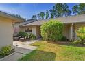 Charming home exterior with a brick patio seating area, lush landscaping, and a well-maintained lawn at 3274 Lori Ln # 2, New Port Richey, FL 34655