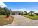 Beautifully landscaped home showcasing a paver driveway, lush lawn, and mature palm tree at 3400 Rosebay Ct, Spring Hill, FL 34609