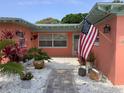 Inviting front porch featuring beautiful landscaping and an American flag at 406 Driftwood E Dr, Palm Harbor, FL 34683