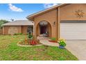 Charming home exterior with manicured flower beds, arched entryway, and attached two-car garage at 4190 Lema Dr, Spring Hill, FL 34609