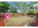 Spacious backyard featuring a wooden fence, mature trees, and a playhouse at 9111 Greenbriar Ln, Port Richey, FL 34668